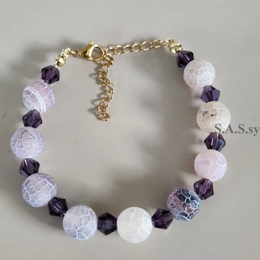 Bracelet with purple and white beads on a neutral background
