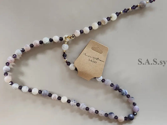 Beaded necklace with a brown tag on a light gray background
