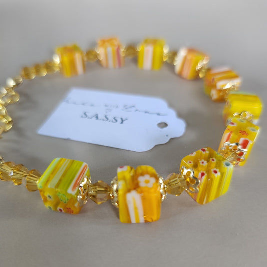 Beaded bracelet with yellow and white pattern on a gray background