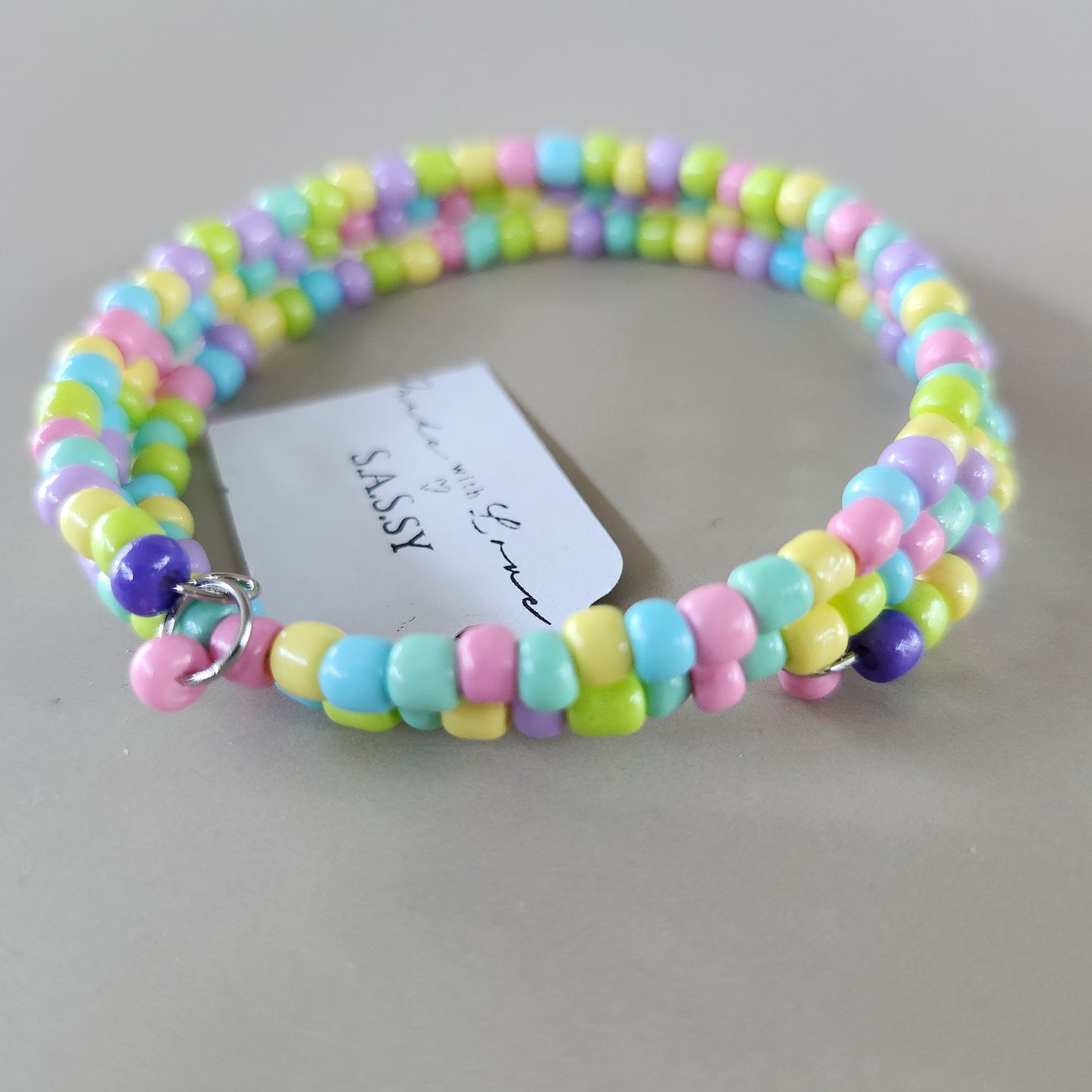 Colorful beaded bracelet with a 'SASSY' card on a light gray background