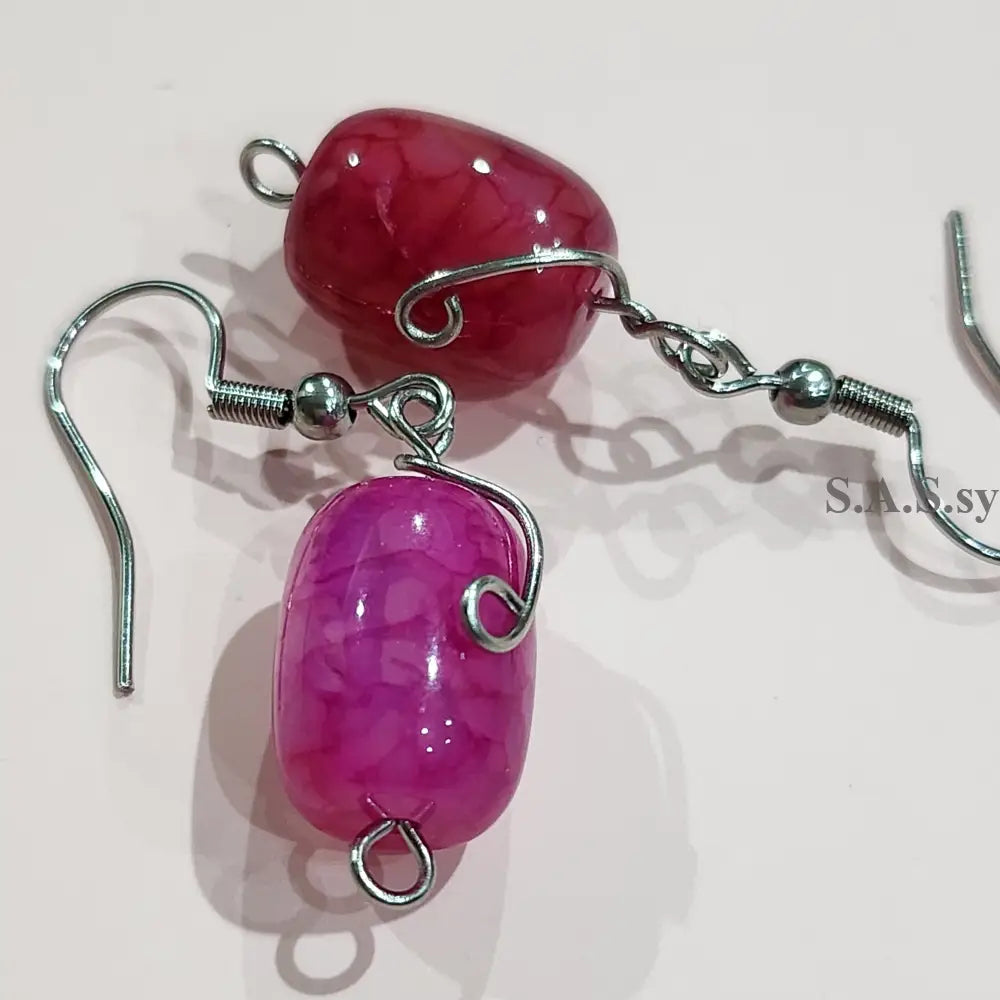 Pink beaded earrings with silver hooks on a light pink background