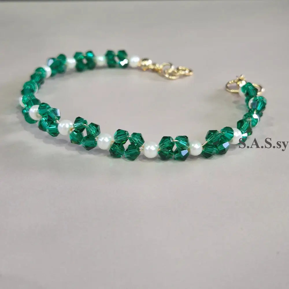 Green and white beaded bracelet on a gray background