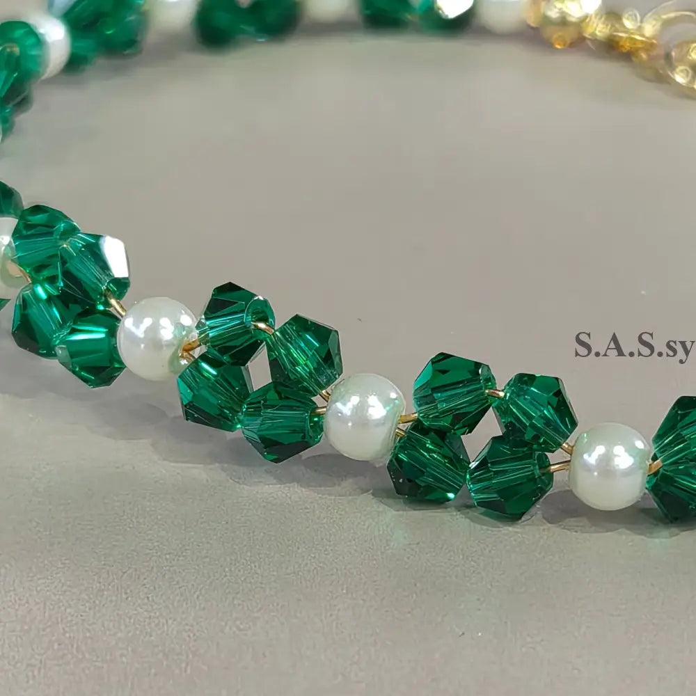 Close-up of a beaded bracelet with green and white beads on a neutral background