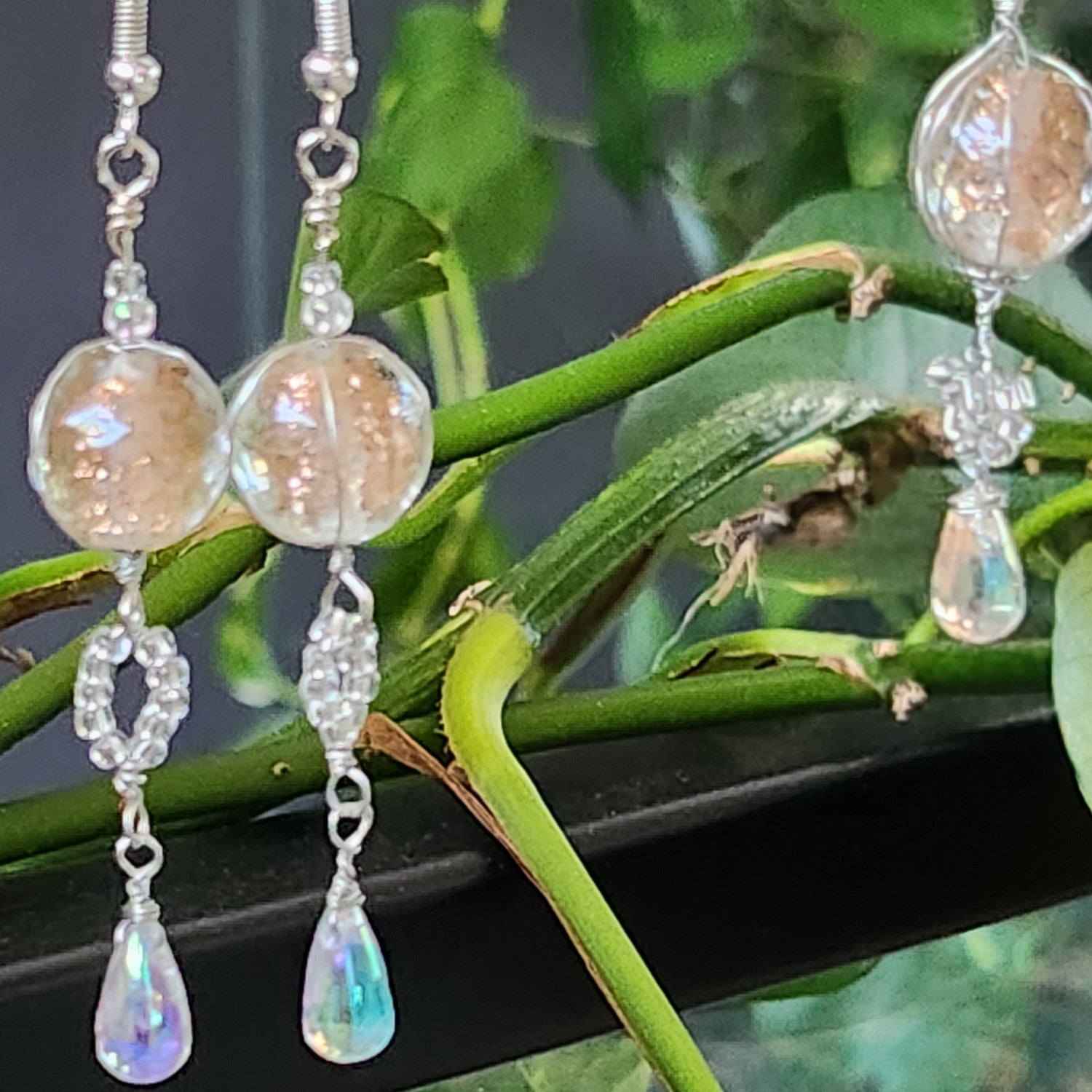 Beaded earrings hanging on a branch with green leaves