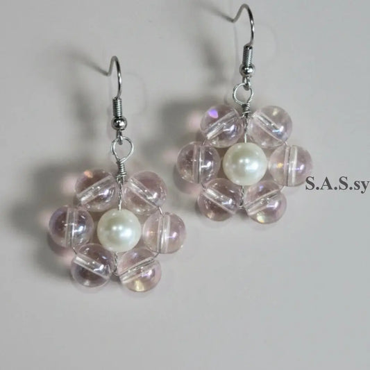 Pair of earrings with clear pink beads and a central pearl on a light background