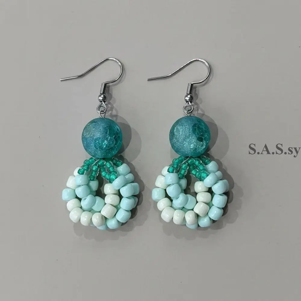 Beaded earrings with sea green and white beads on a neutral background