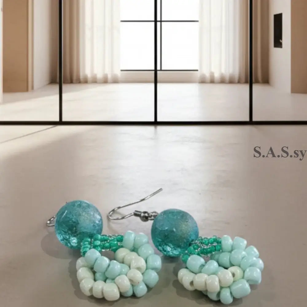 Pair of beaded earrings with blue and green beads on a beige background