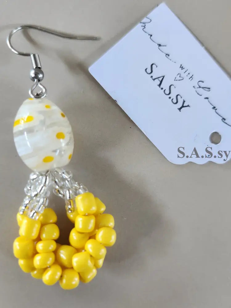 Beaded earrings with yellow and white beads on a beige background