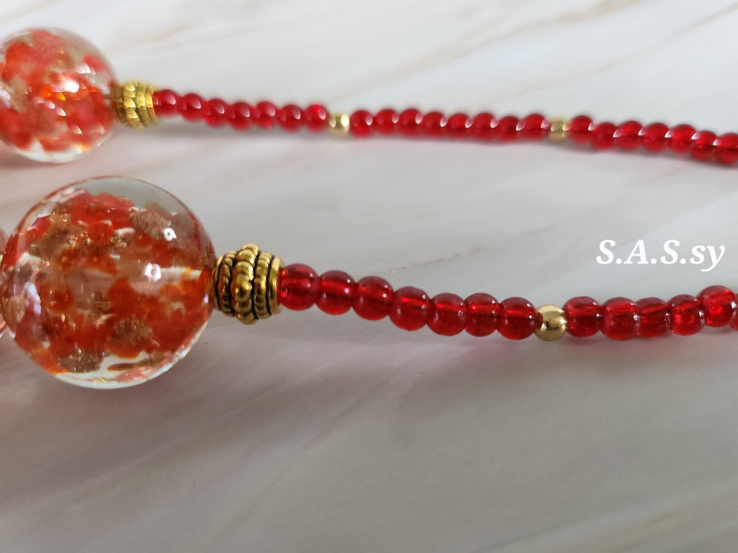 Beaded necklace with red and gold beads on a white background