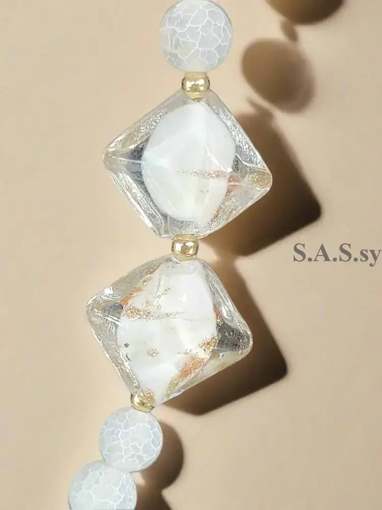 Necklace with white gemstone beads and gold accents on a neutral background.