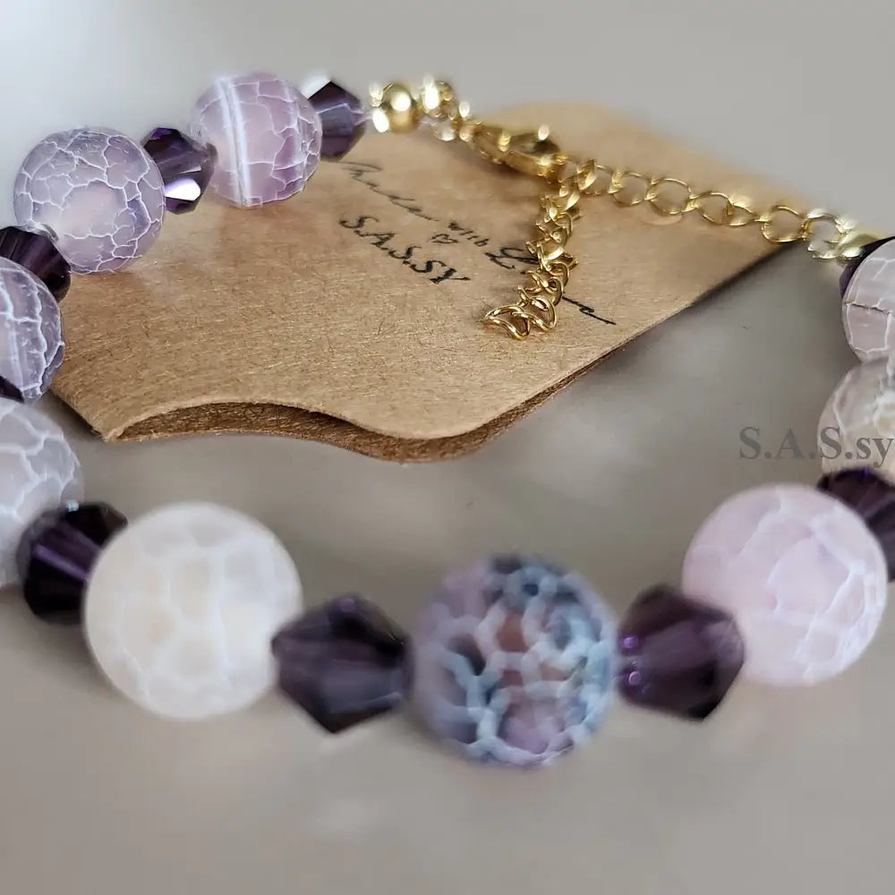 Beaded bracelet with purple and white beads on a neutral background
