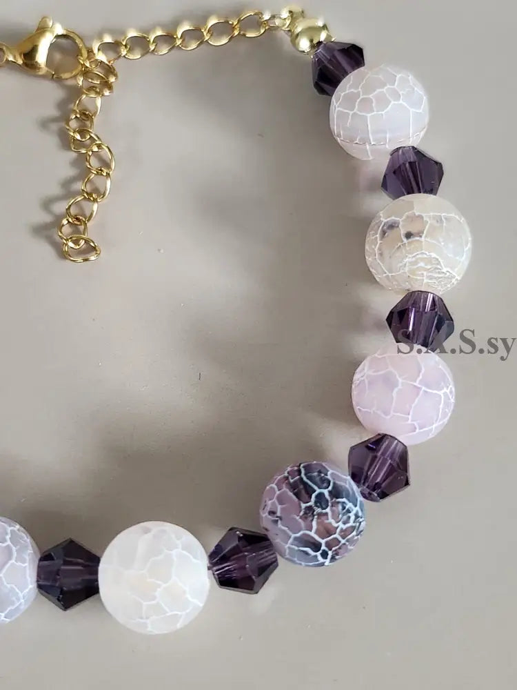 Bracelet with gold chain and multicolored gemstone beads on a light background