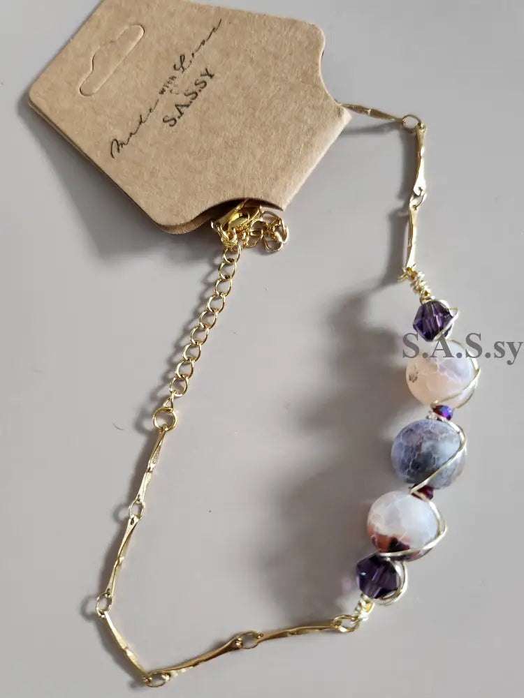 Bracelet with beads and gold chain on a gray background