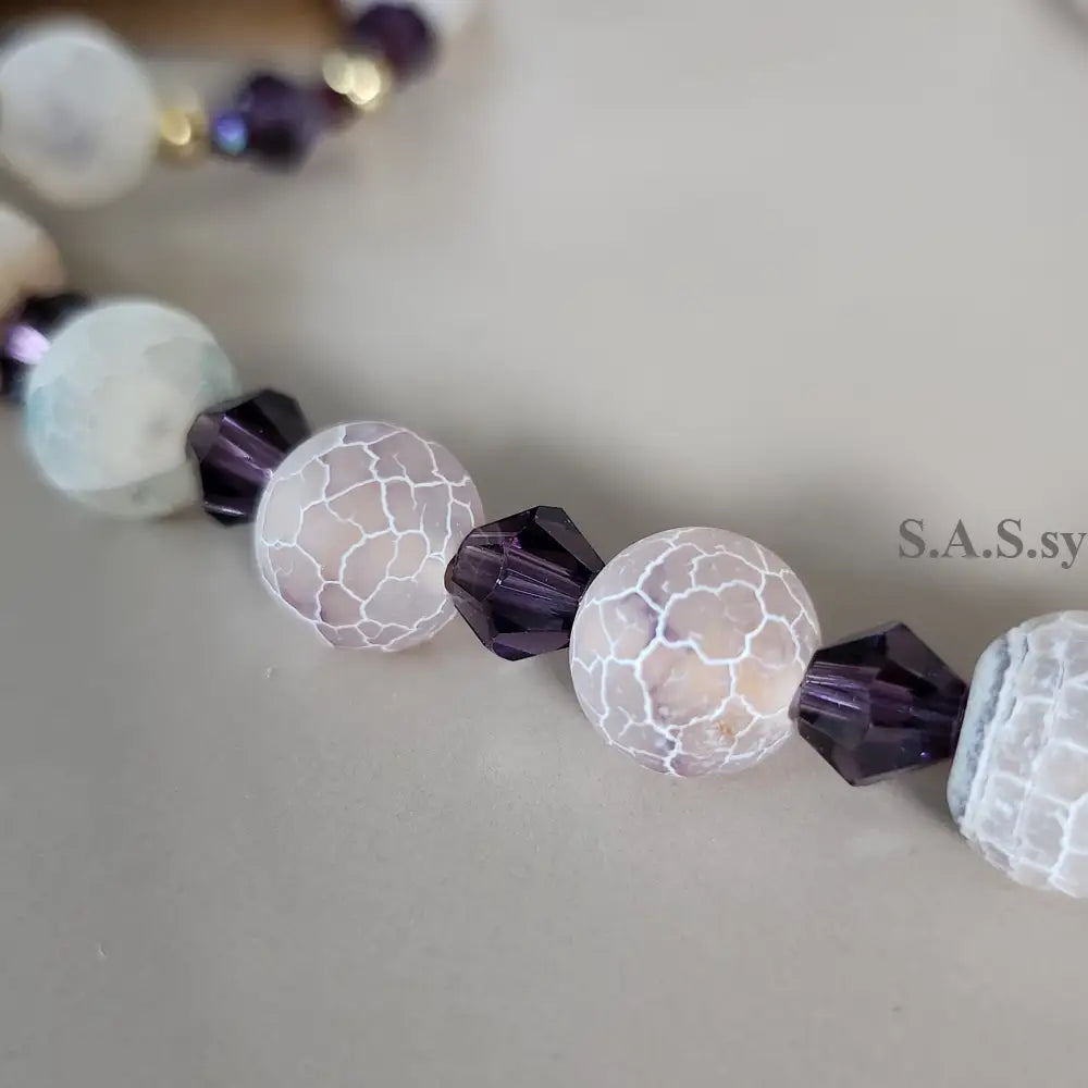 Necklace with white and purple gemstone beads on a neutral background