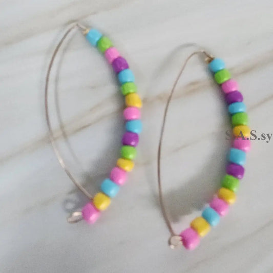 A pair of colourful bead earrings with silver accents, displayed against a marble background.