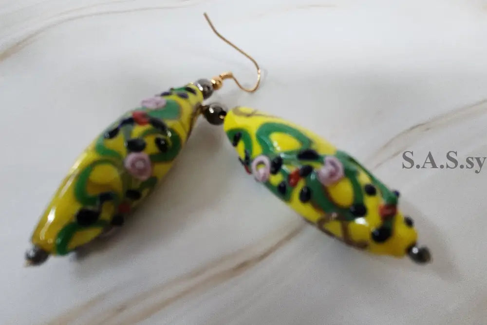 yellow, green, black beaded earrings on marble  surface