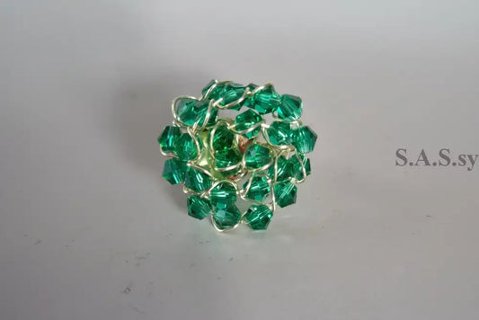 Gold ring with green crystals on a gray background