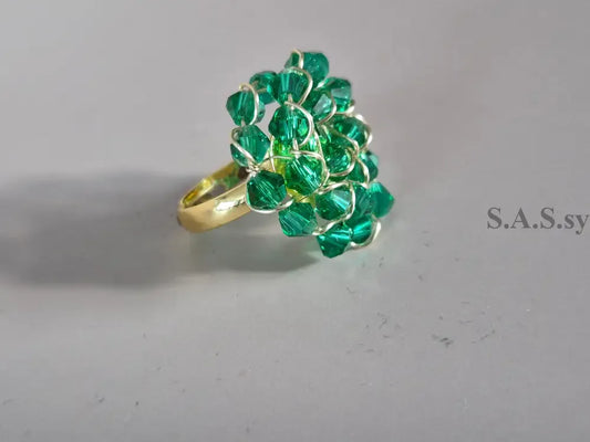 Gold ring with green crystals on a gray background