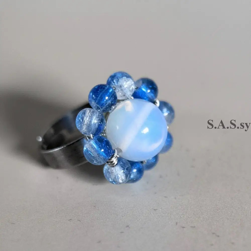 Ring with blue and clear opalite gemstones on a gray background
