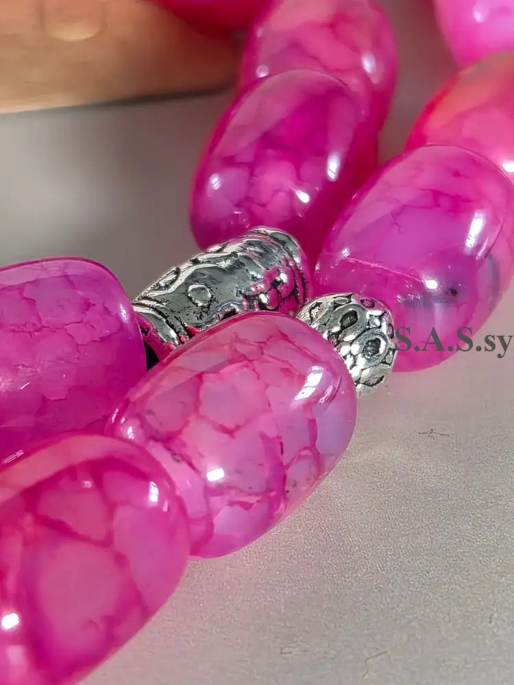 Close-up of pink gemstone beads with silver beads on a neutral background