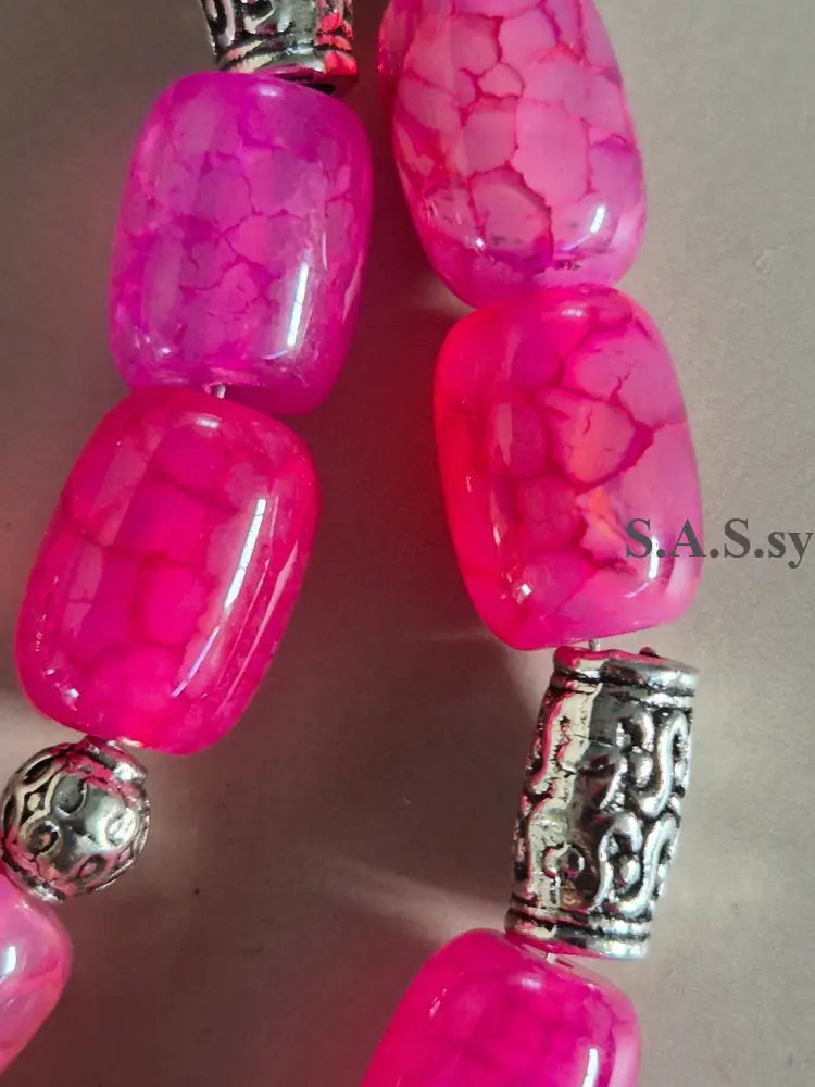 Close-up of pink gemstone beads with silver beads on a neutral background