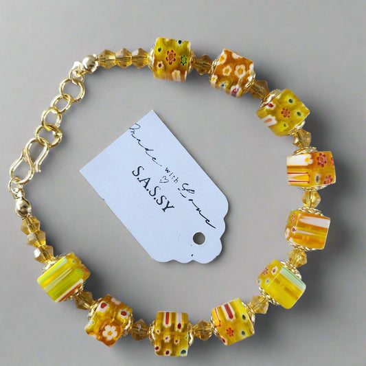 Beaded bracelet with yellow and orange beads on a gray background, featuring a 'SASSY' tag.