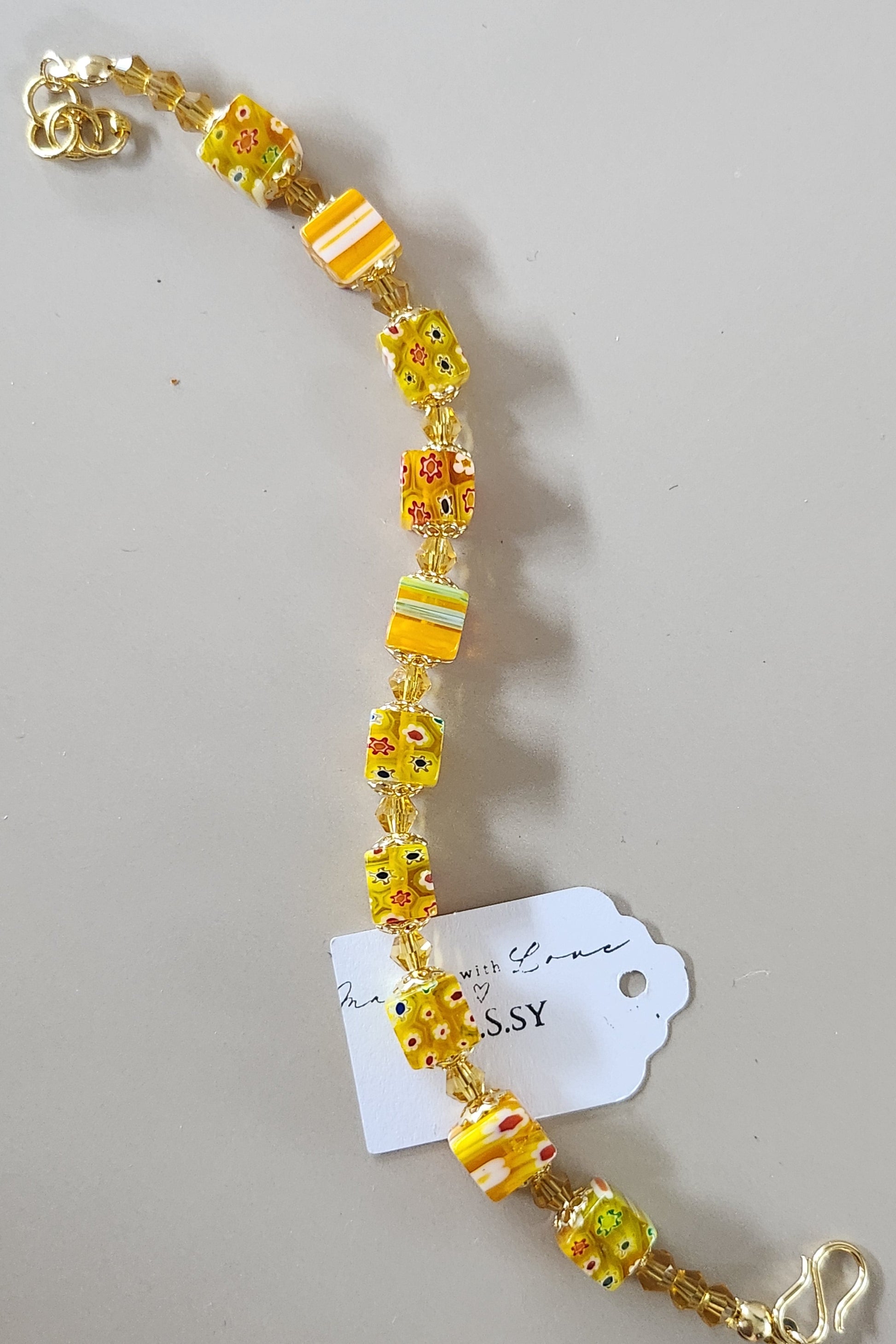 Yellow beaded bracelet with a gold clasp on a gray background