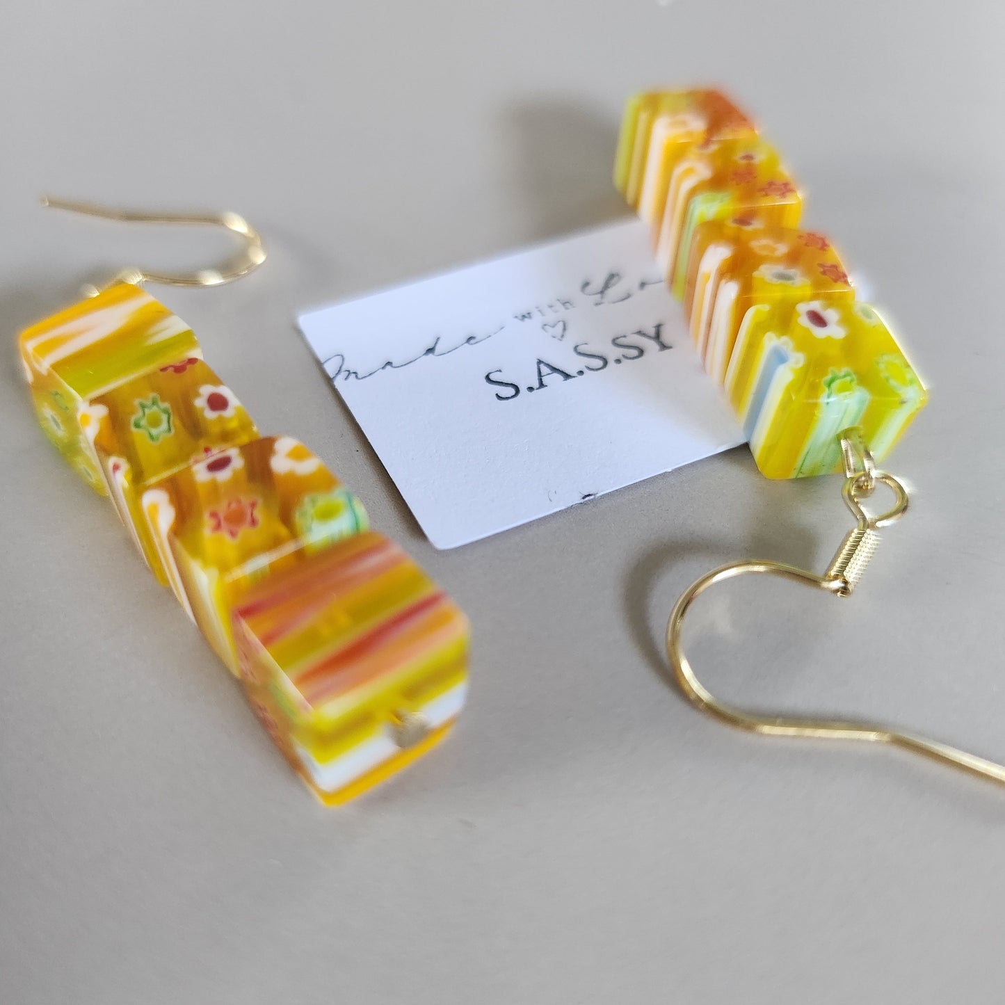 Colorful striped earrings with a gold hook on a gray background