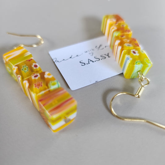 Colorful striped earrings with a gold hook on a gray background