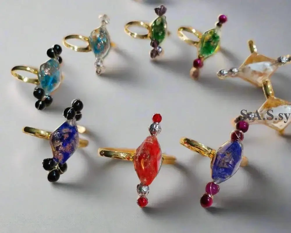 Nine vivid coloured cocktail rings on a light surface - Sassy by Sharmin Aziz 